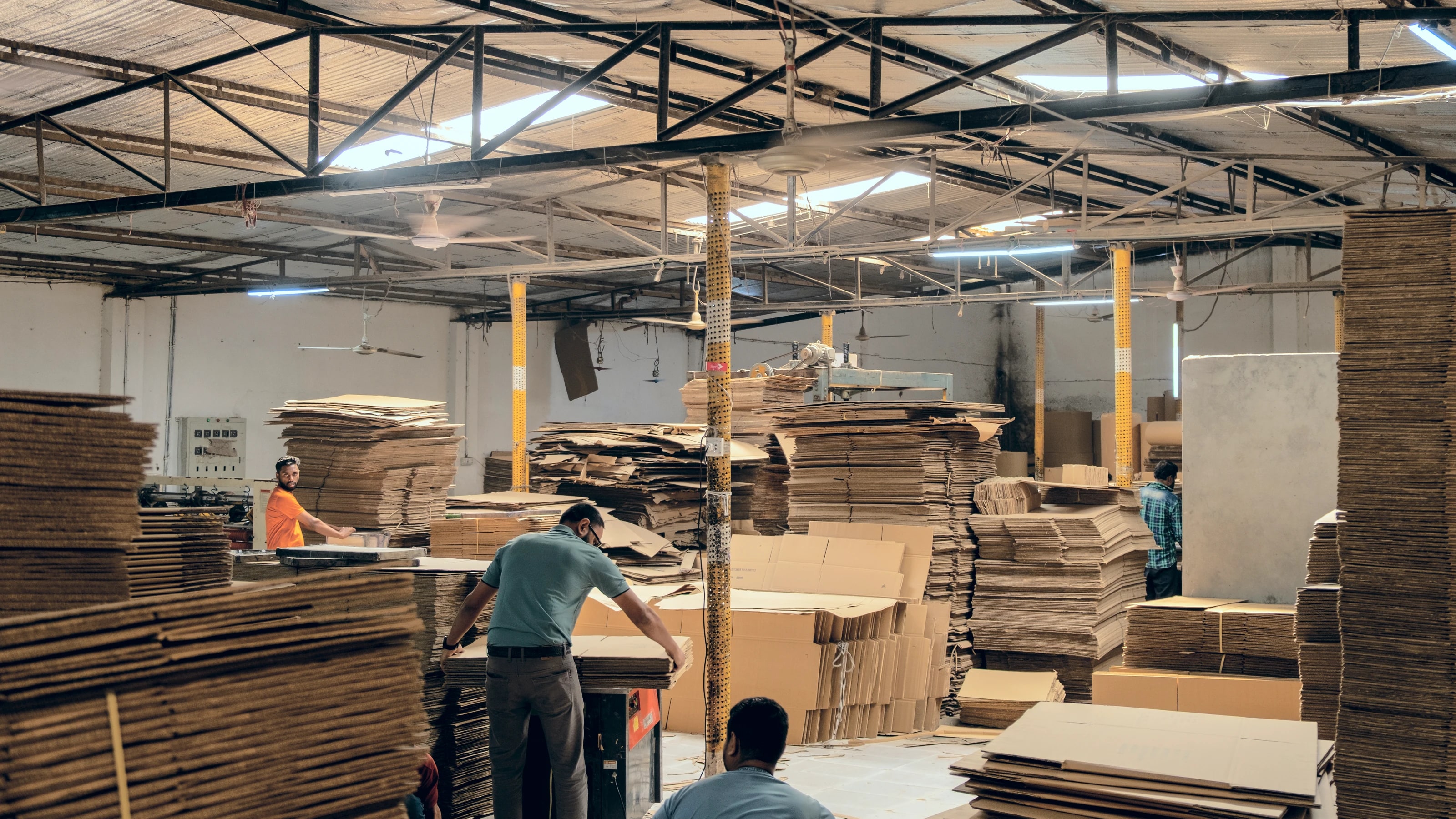 Corrugation floor at the Ashulia facility, stacks of cut board and the team working